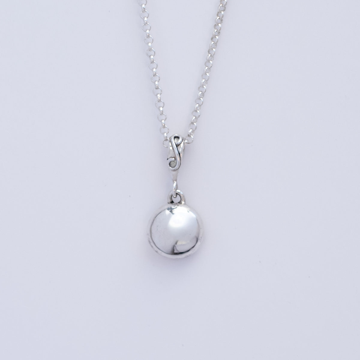 Silver necklace with a round Argentium smooth pebble pendant on a light gray background