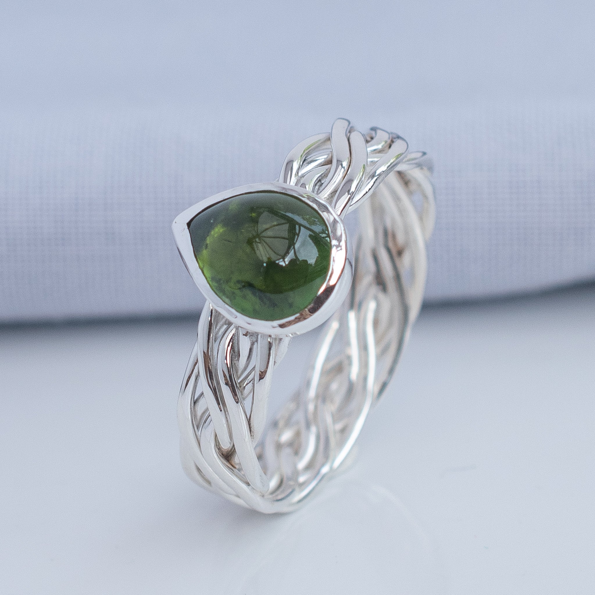 Close-up of natural olive green tourmaline in a polished silver setting