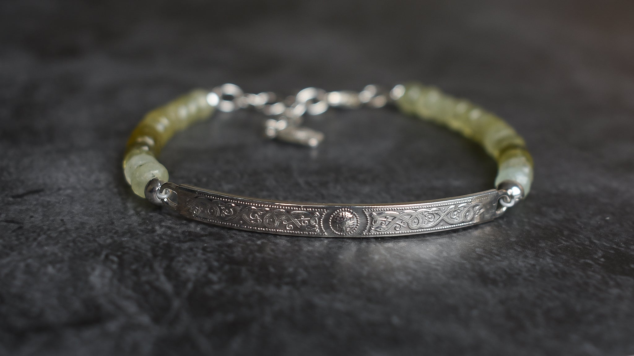 A Grossular Garnet beaded Bracelet with faceted Garnets ranging in colur fro soft grass green to olive and brown tones. Sterling Silver Celtic Bar with a main done surrounded by engraved scroll work. 