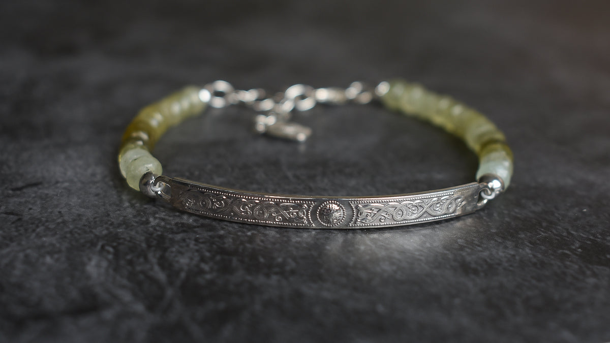 A Grossular Garnet beaded Bracelet with faceted Garnets ranging in colur fro soft grass green to olive and brown tones. Sterling Silver Celtic Bar with a main done surrounded by engraved scroll work. 