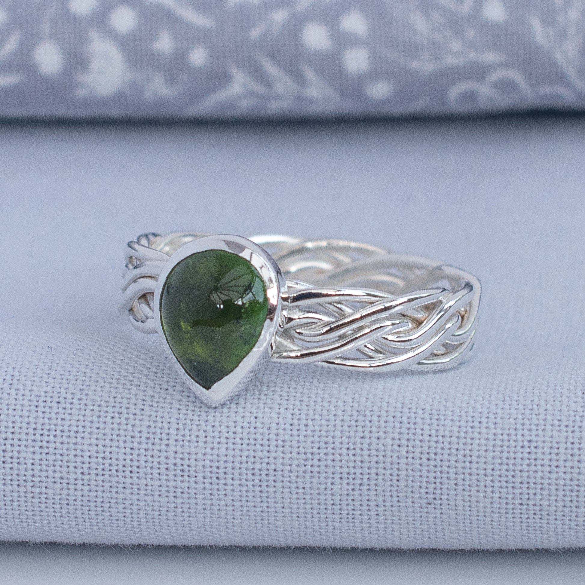Side view of olive green tourmaline ring with woven Argentium silver band