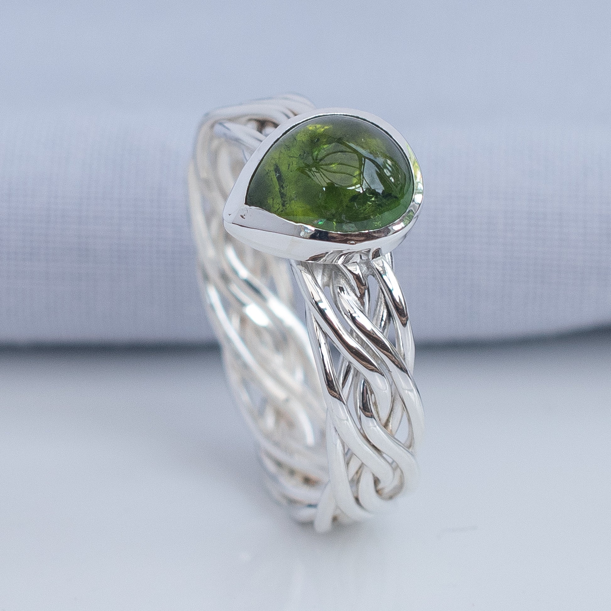 Handwoven silver ring band with crossing strands and pear-shaped tourmaline